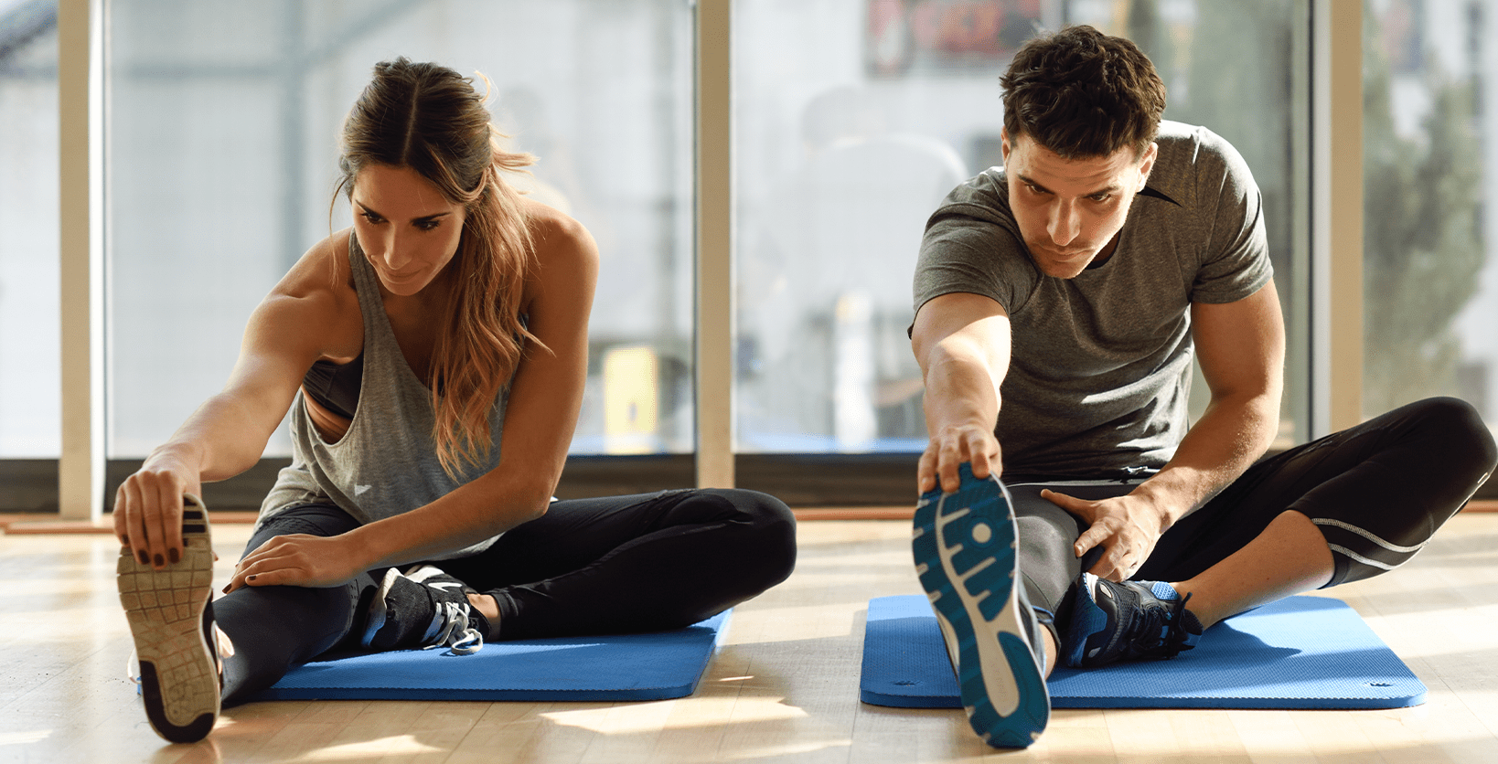  A young woman and a young man stretch their legs before exercising.