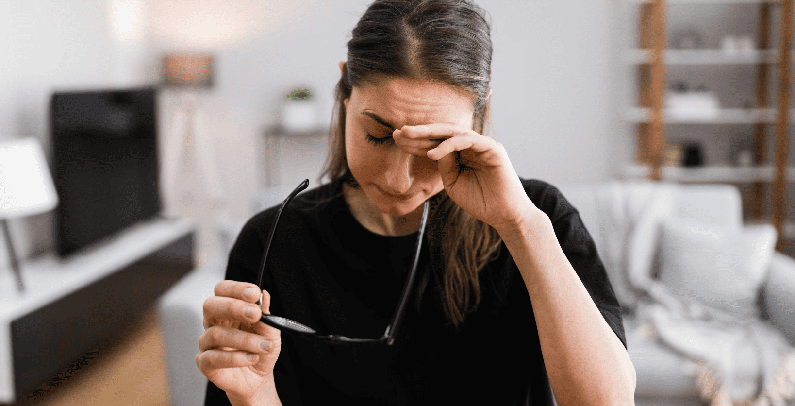 woman removing classes and holding hand to her brow