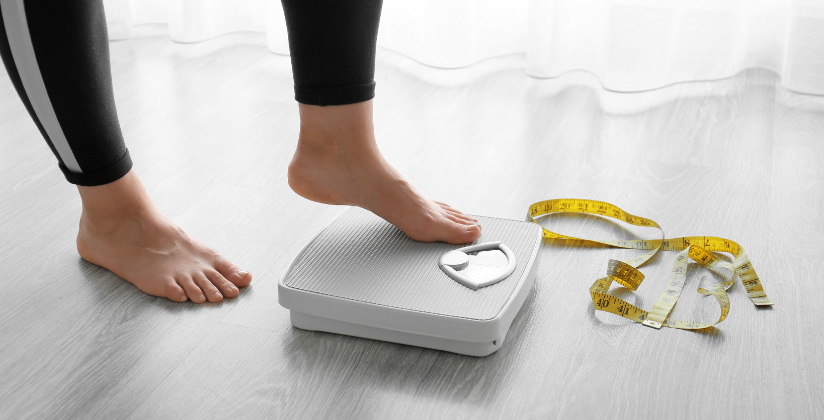 Woman sits on floor with bowl of salad on her lap and exercise weights on the floor in front of her.